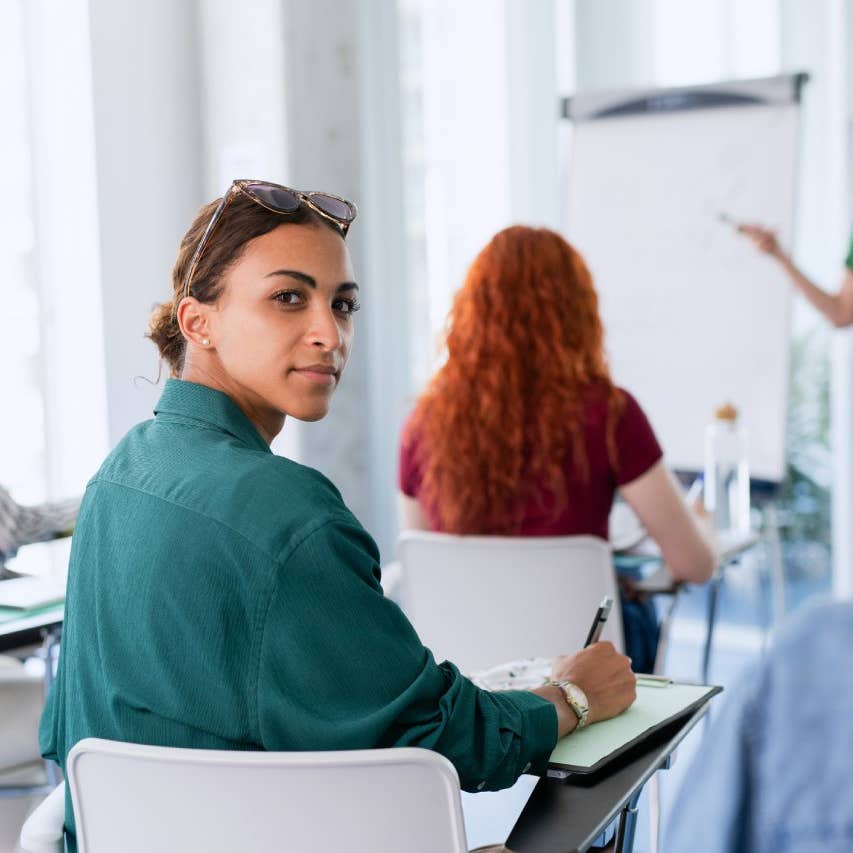 Portrait of young university student sitting in classroom indoors, looking at camera.