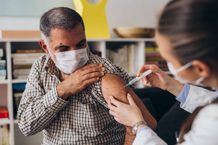Senior wearing a face mask receiving a vaccine injection