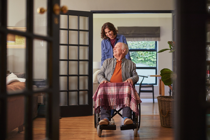 A woman pushing her parent in a wheelchair.